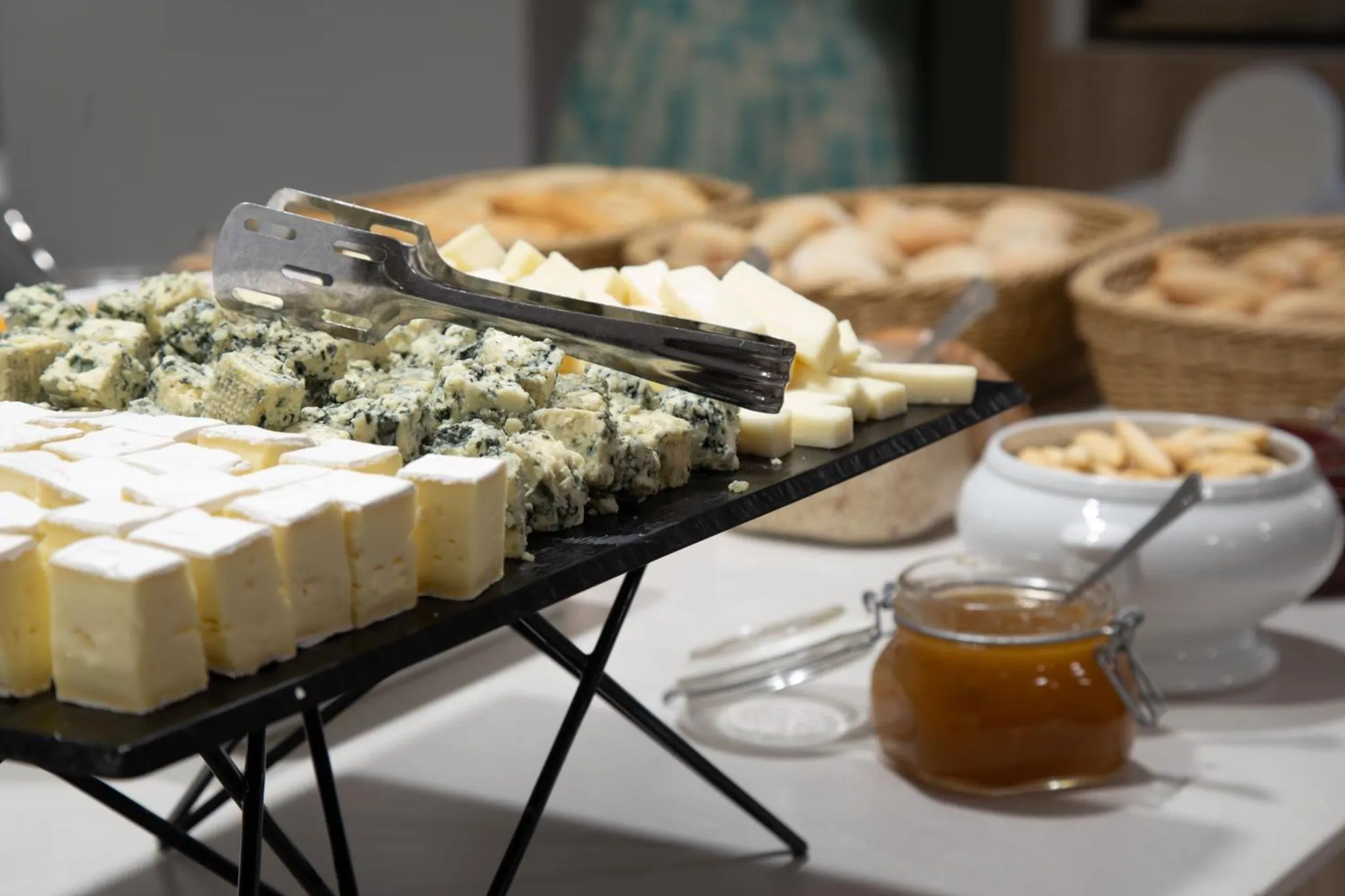 Présentation de fromages variés et de confiture sur un buffet.