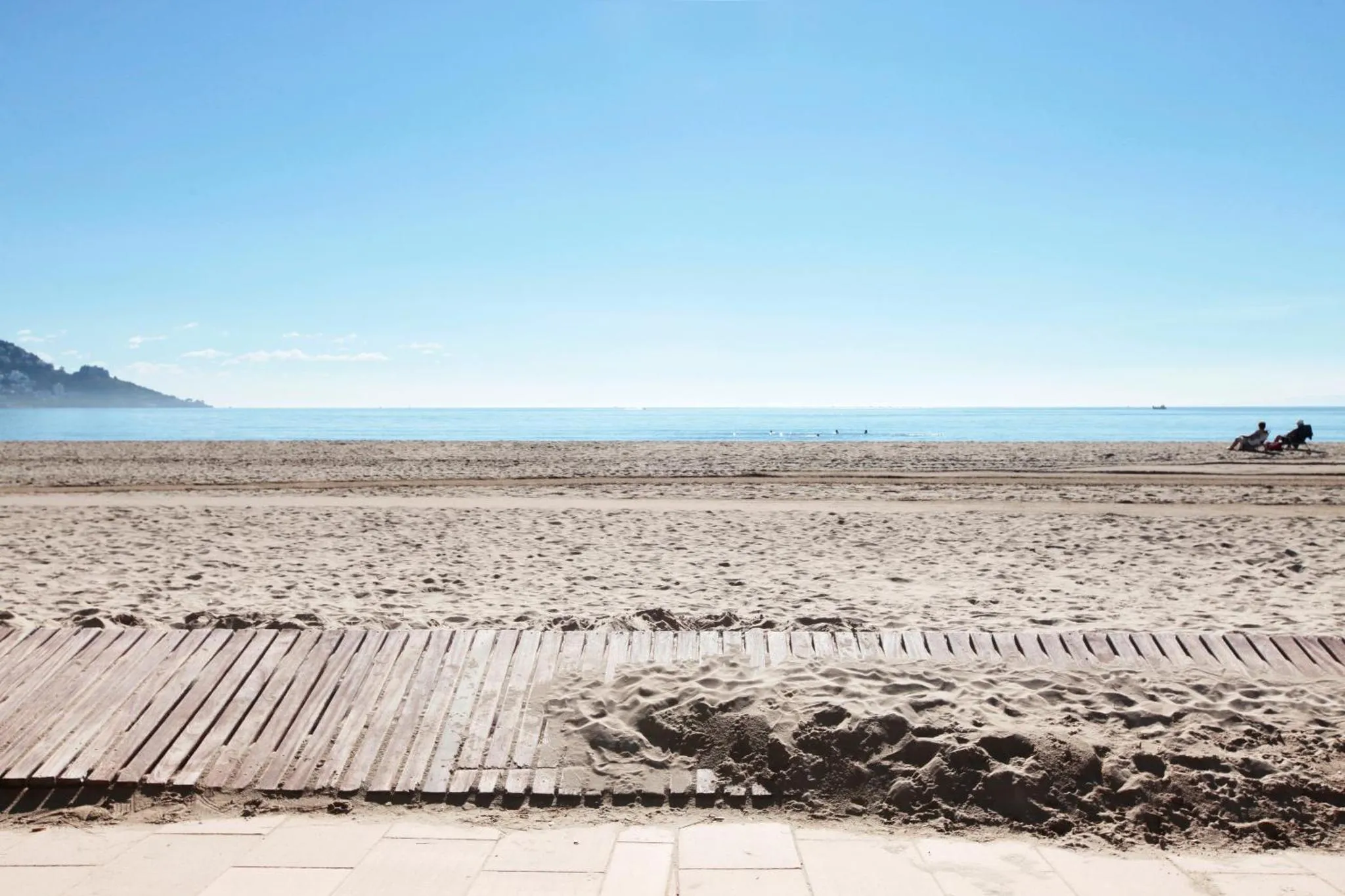 Plage de sable fin avec vue sur la mer et le ciel bleu.