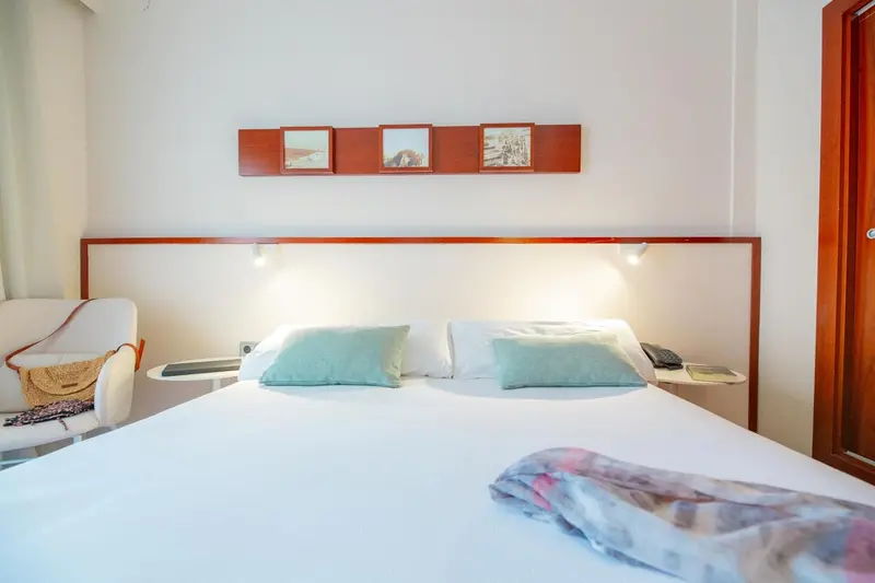 Une chambre lumineuse avec un grand lit et des coussins verts.