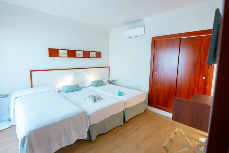 Une chambre lumineuse avec deux lits simples et une décoration sobre.