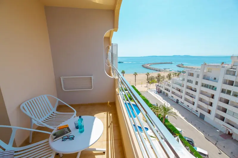 Une terrasse ensoleillée offre une vue sur la mer et la ville.