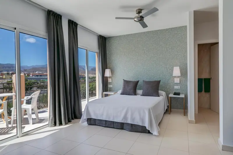 Une chambre lumineuse avec un grand lit et un accès à une terrasse.