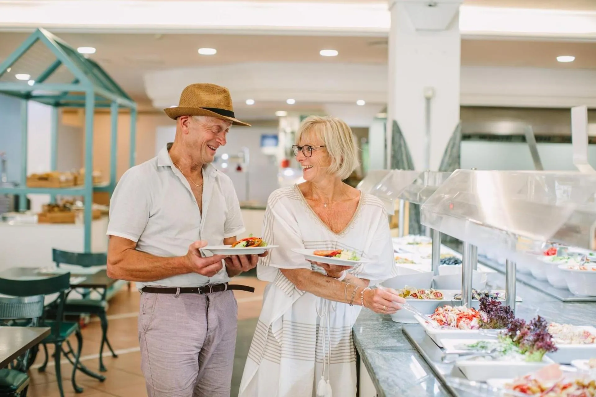 Un couple souriant se sert au buffet d'un restaurant.