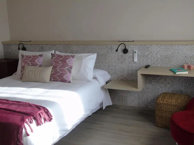 Une chambre lumineuse avec un grand lit décoré de coussins.