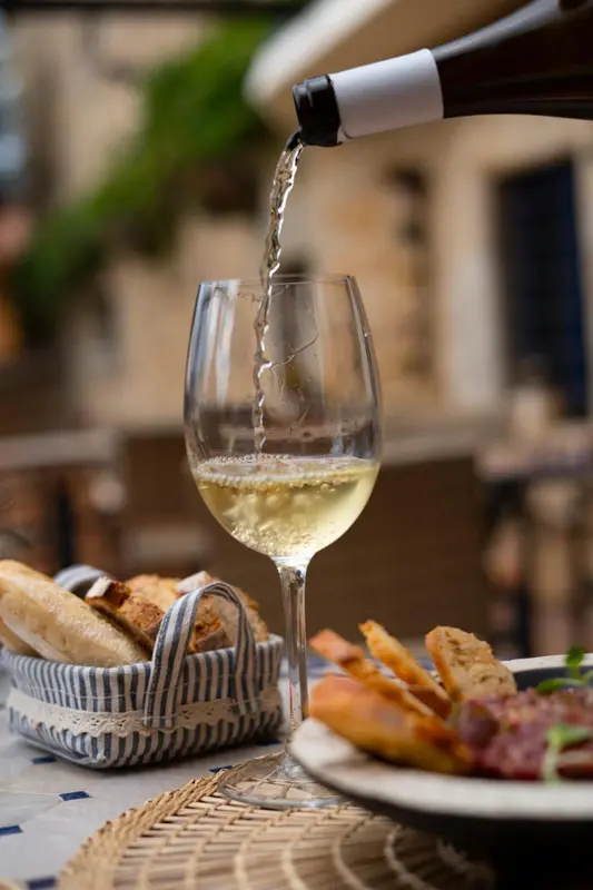 Un verre de vin blanc se remplit sur une table avec des amuse-gueules.