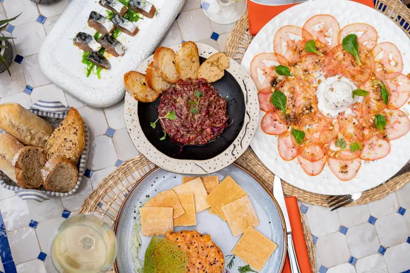 Assiettes de mets variés présentées sur une table carrelée en extérieur.