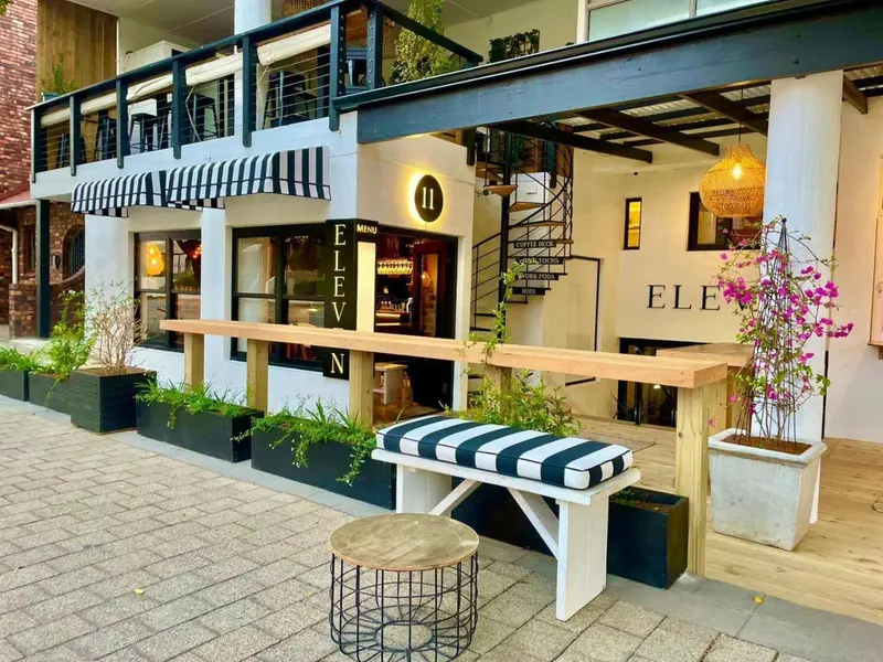 Façade d'un établissement avec une terrasse et des tables en bois.