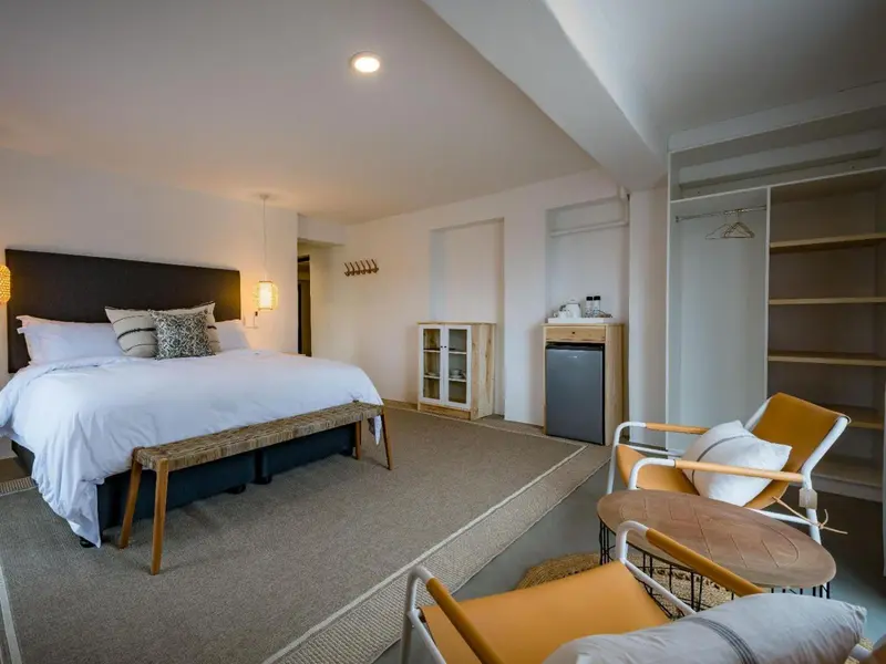 Une chambre lumineuse avec un grand lit et un coin salon.