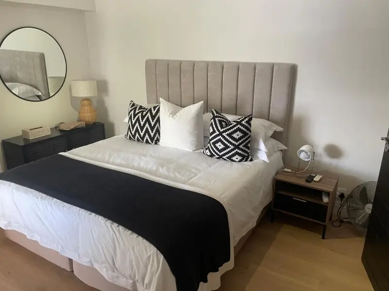 Une chambre avec un grand lit recouvert d'une couverture blanche et noire et de coussins décoratifs.