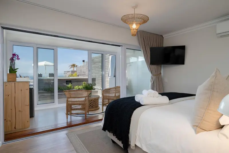 Une chambre lumineuse avec un grand balcon donnant sur la mer.