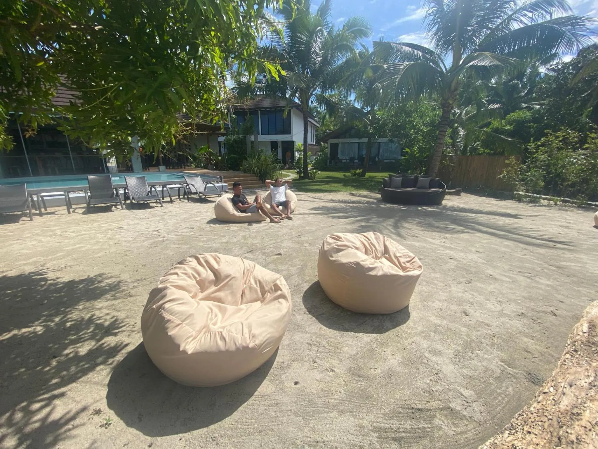 Deux personnes se détendent sur des fauteuils en extérieur près d'une piscine.