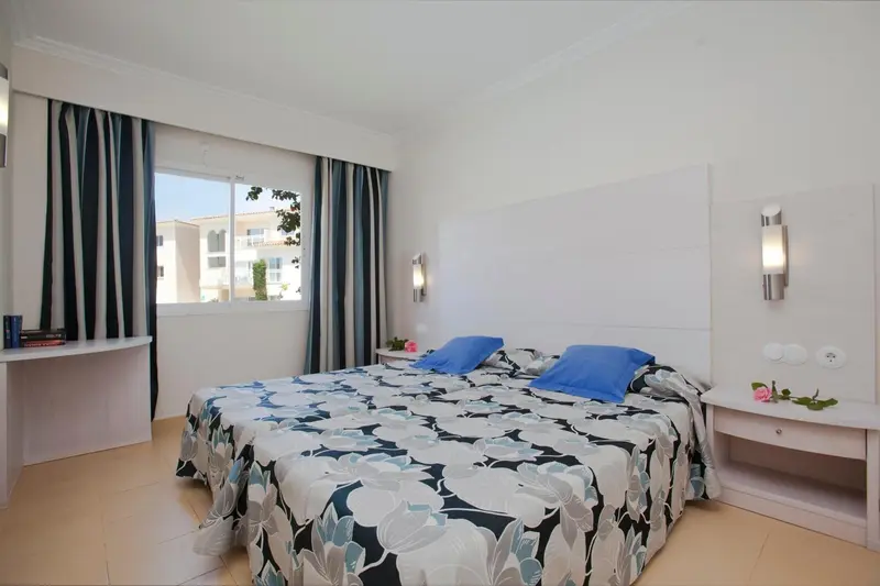 Une chambre lumineuse avec un grand lit recouvert d'une couette à motifs.