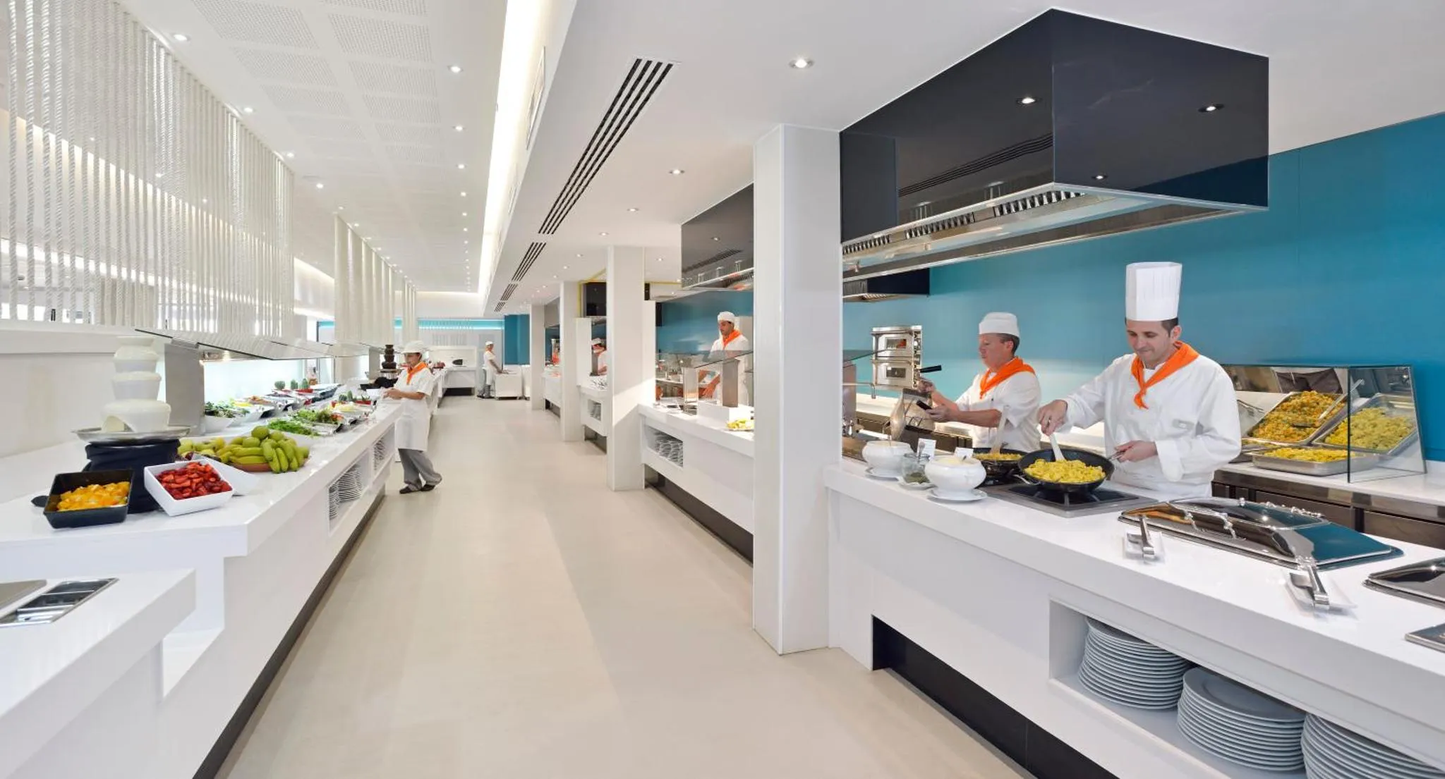 Un buffet propose une variété de plats préparés par des chefs en uniforme.