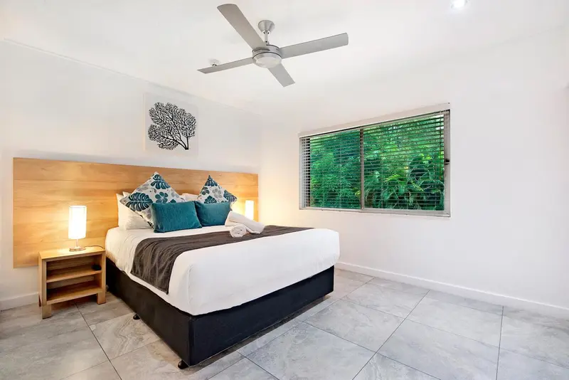 Une chambre lumineuse avec un grand lit recouvert d'oreillers et d'une couverture.