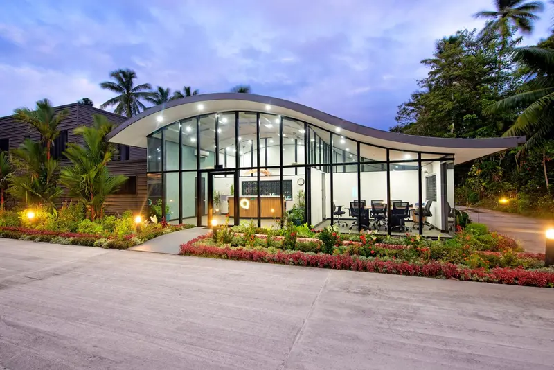Bâtiment moderne avec une façade vitrée et un jardin soigné.