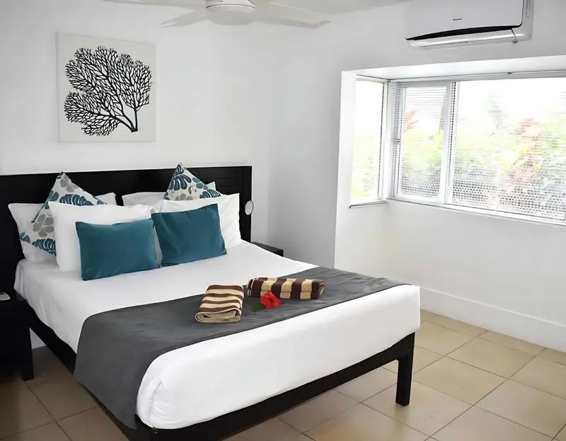 Une chambre lumineuse avec un grand lit recouvert d'oreillers et d'une couverture décorative.