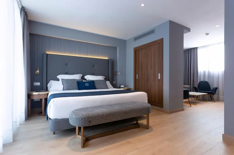 Une chambre moderne avec un grand lit et un banc au pied du lit.