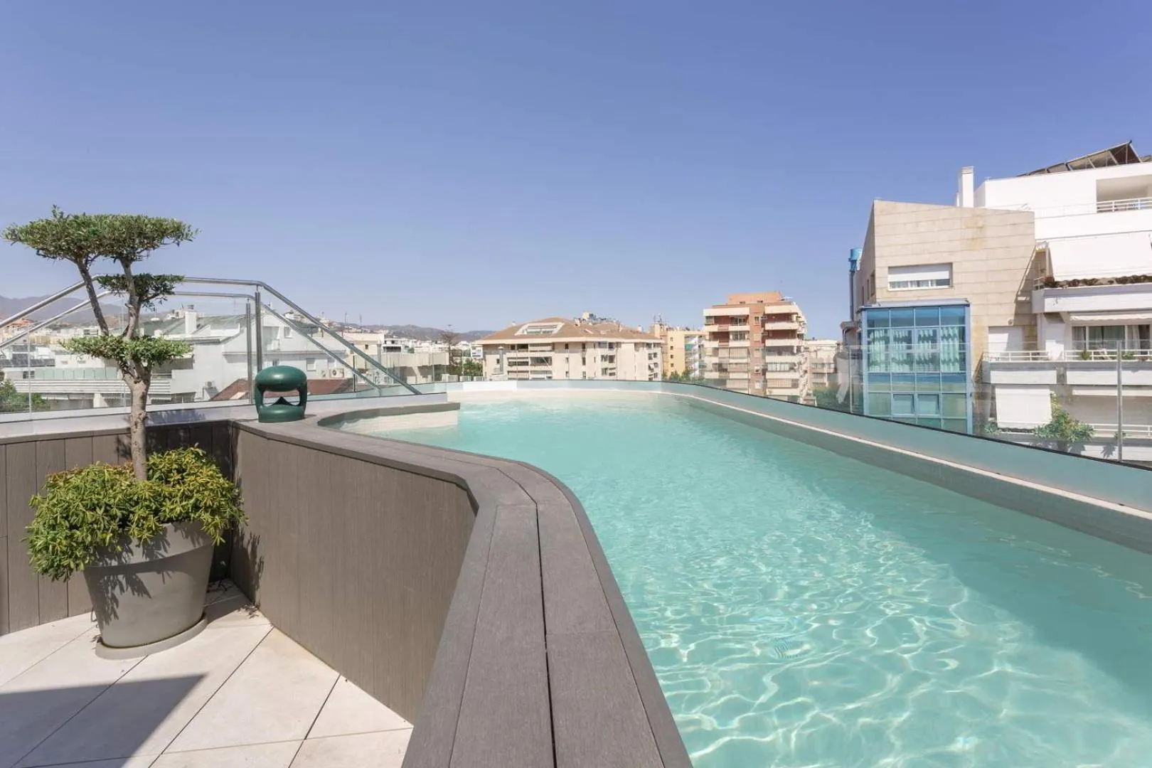 Piscine à débordement sur terrasse avec vue sur la ville.