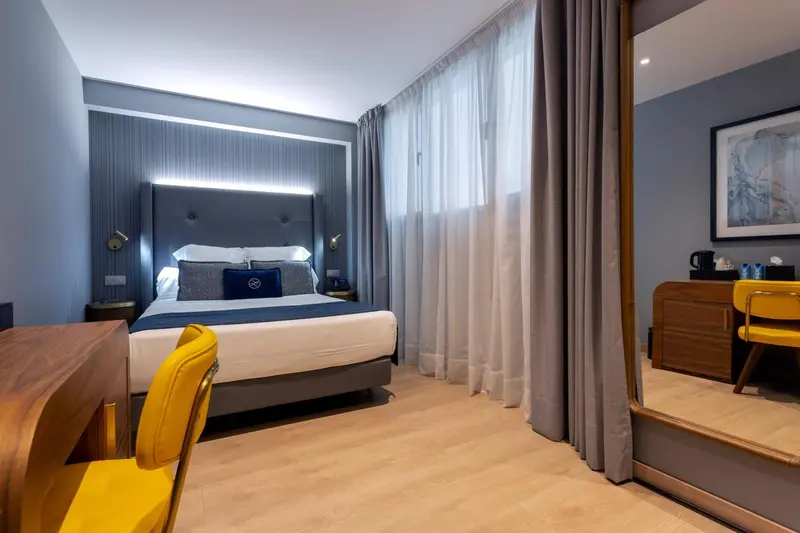 Une chambre moderne avec un grand lit et un bureau jaune.