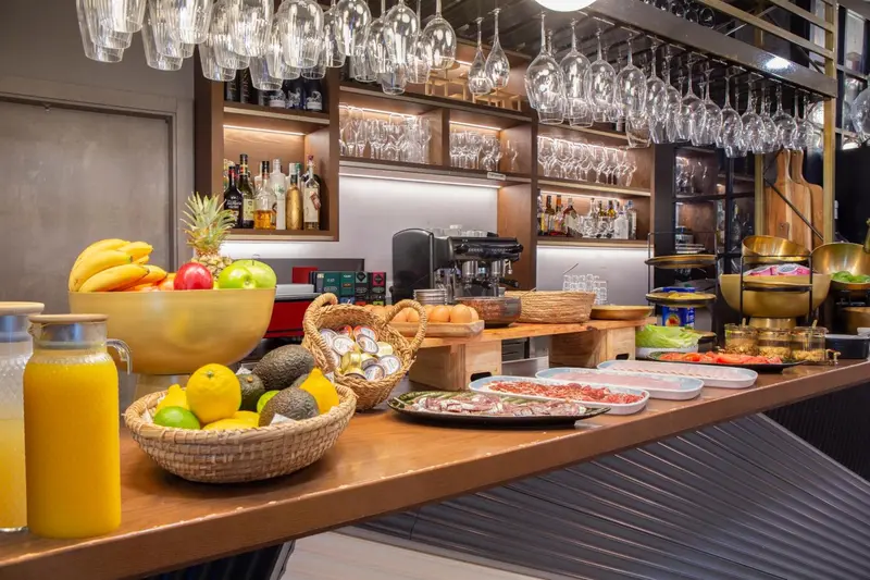 Un comptoir de buffet propose des fruits frais, des viennoiseries et des boissons.