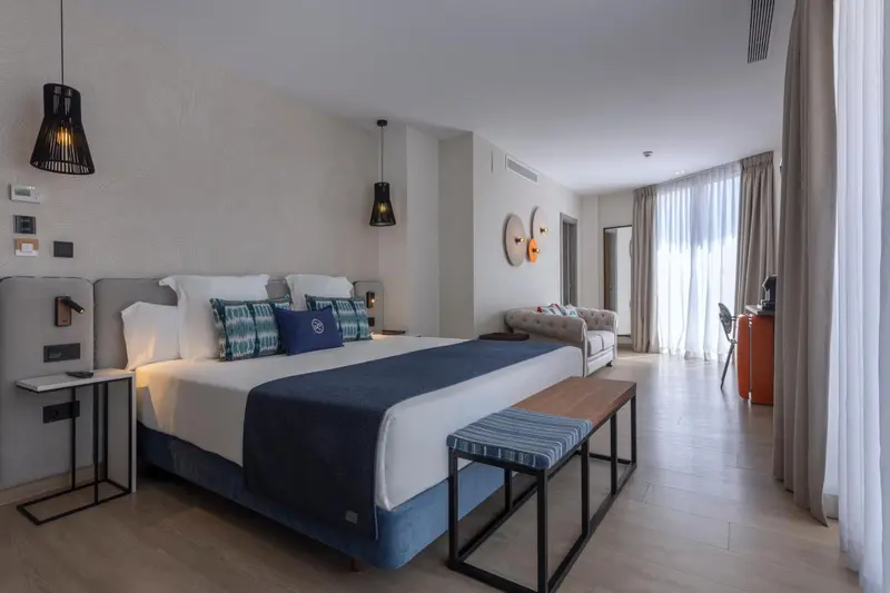 Une chambre lumineuse avec un grand lit et un coin salon.