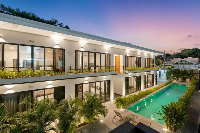 Façade d'un bâtiment blanc avec de grandes baies vitrées donnant sur une piscine.
