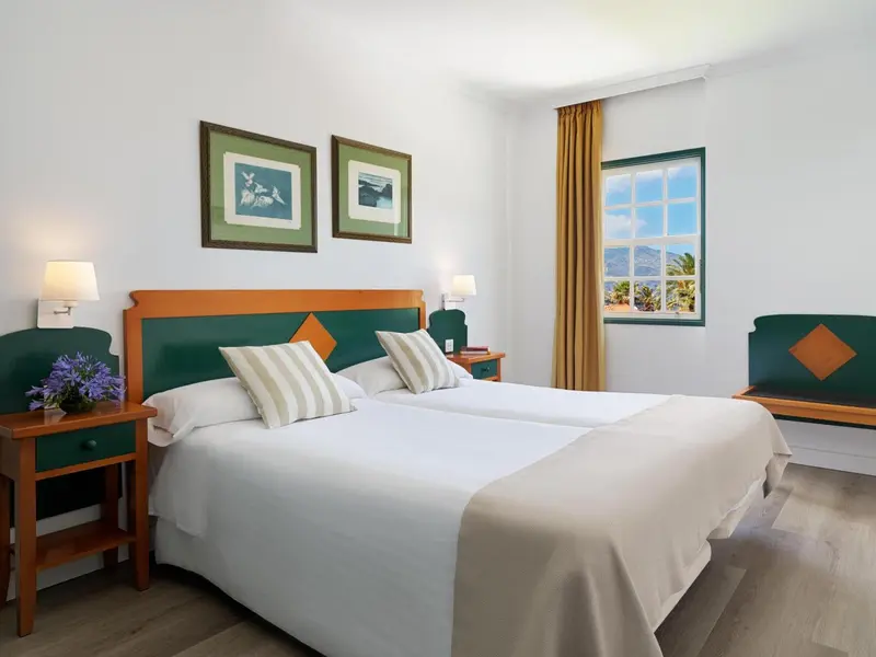 Une chambre lumineuse avec un grand lit et des tableaux décoratifs.