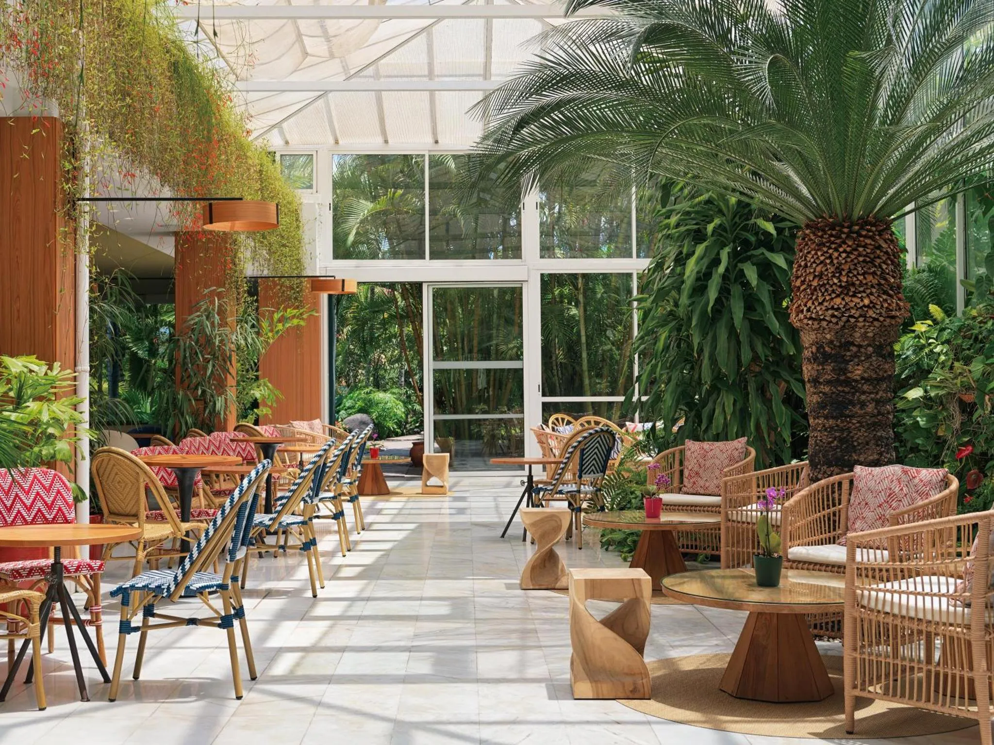 Espace de détente extérieur avec mobilier en rotin et végétation luxuriante.