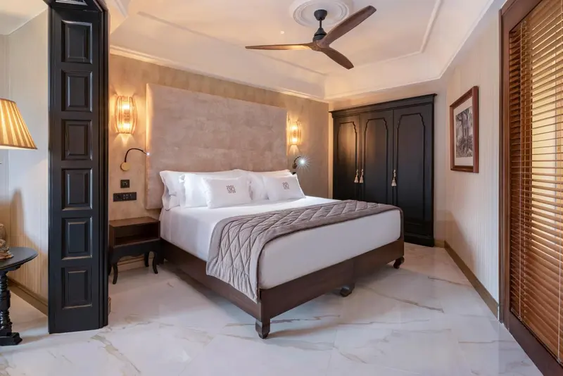 Une chambre lumineuse avec un grand lit recouvert d'une courtepointe blanche et grise.