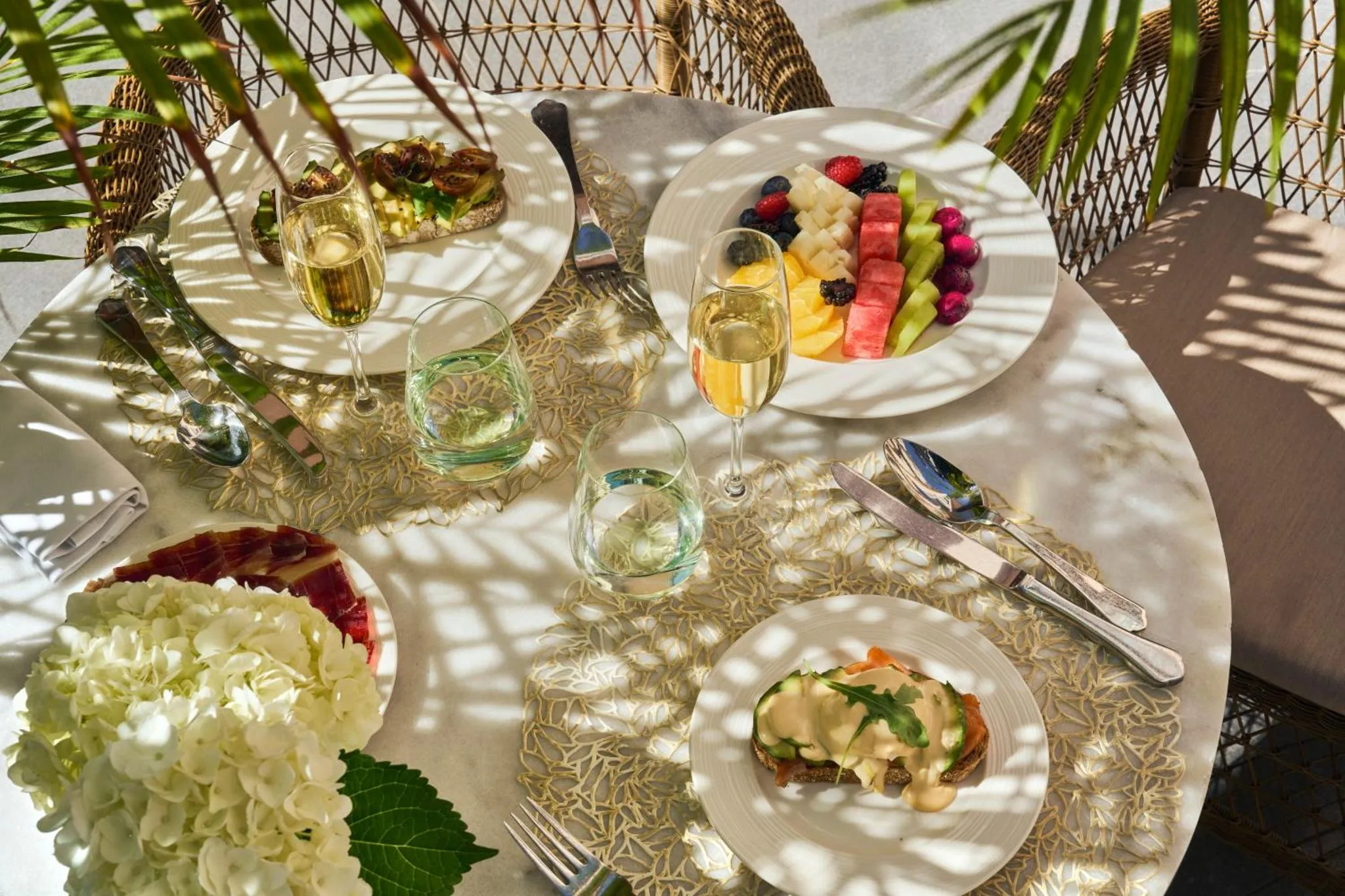 Une table ronde est dressée avec des assiettes de nourriture et des boissons.