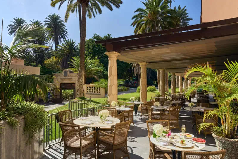 Terrasse ombragée avec tables dressées et végétation luxuriante.