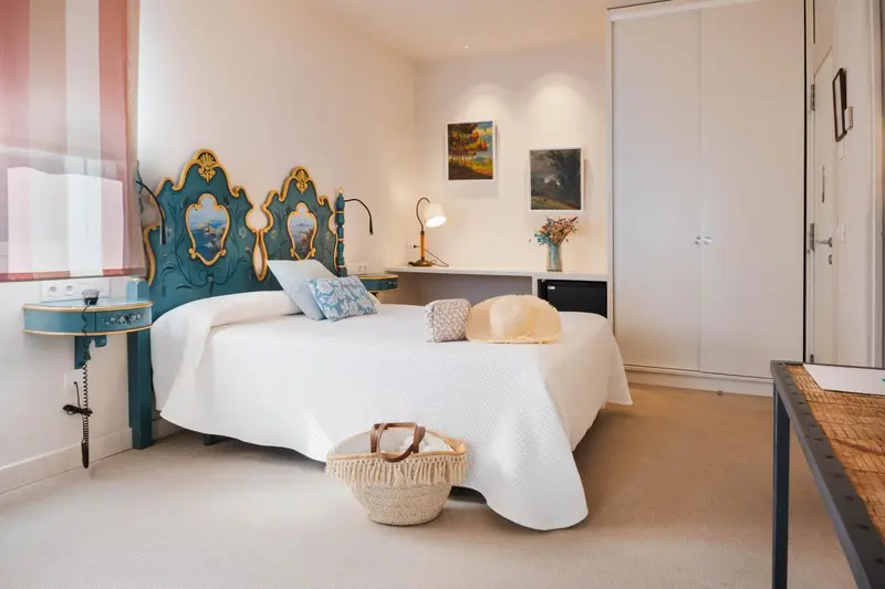 Une chambre lumineuse avec un grand lit décoré d'une tête de lit sculptée.