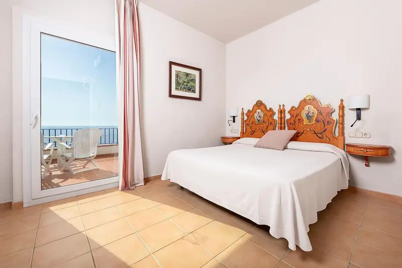 Chambre lumineuse avec un grand lit et un accès à une terrasse.