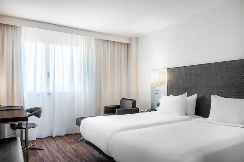 Une chambre lumineuse avec un lit double et un fauteuil.