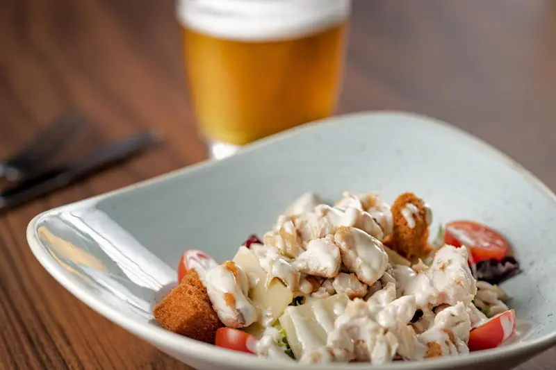 Assiette de salade composée avec des morceaux de poulet et une boisson fraîche.