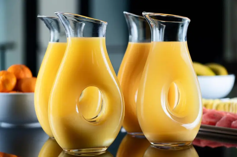 Des carafes de jus d'orange sont présentées sur un buffet.