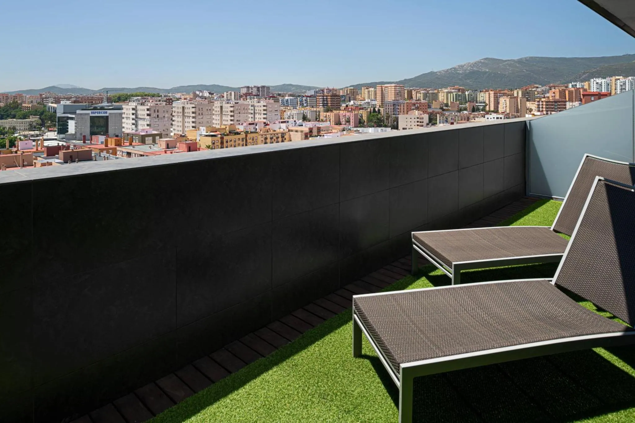 Terrasse avec transats et vue sur la ville et les montagnes.