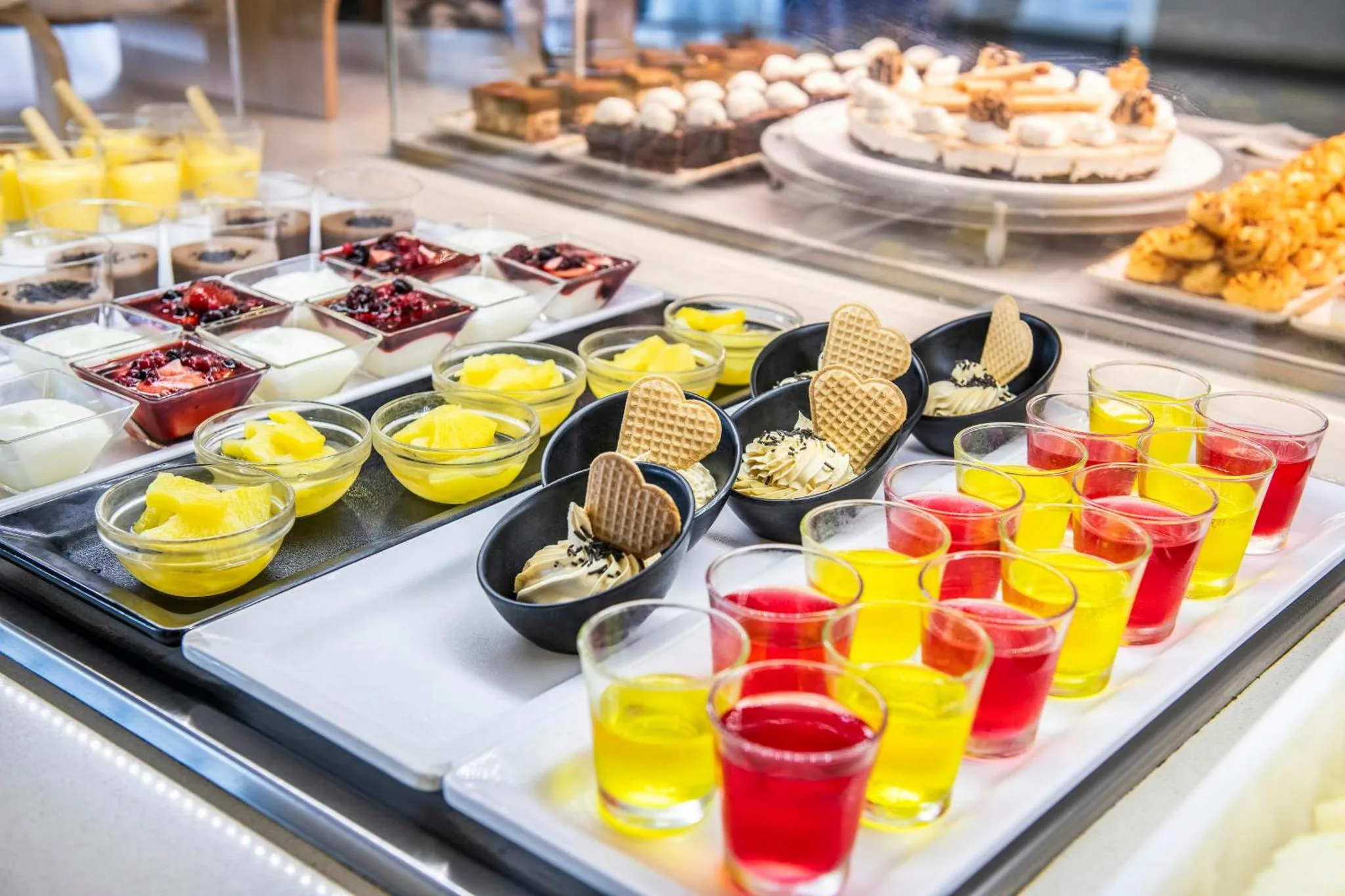 Présentation de desserts variés et de boissons colorées sur un buffet.