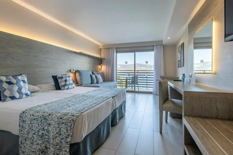 Chambre lumineuse avec lits jumeaux et balcon donnant sur la mer.
