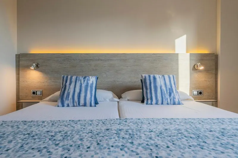 Lit double avec oreillers bleus dans une chambre lumineuse.