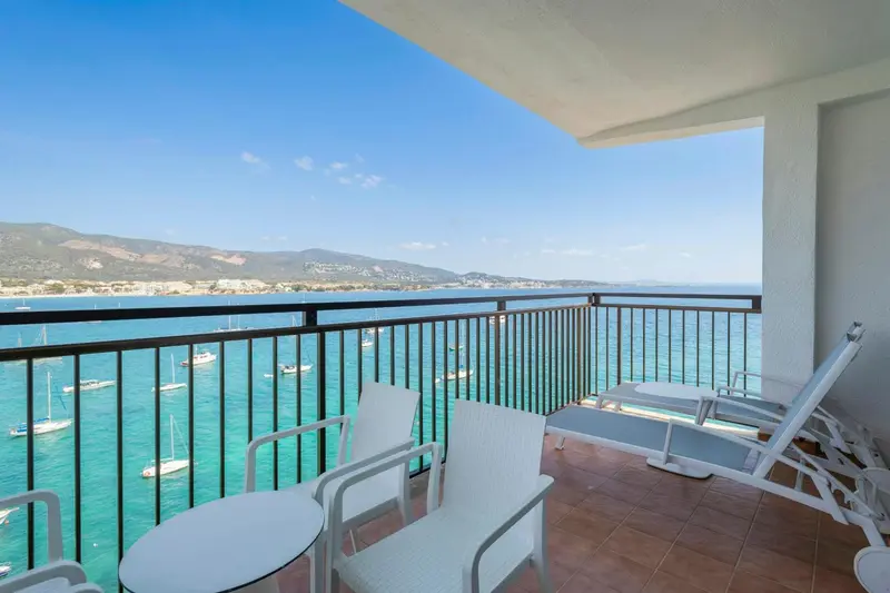Terrasse avec mobilier blanc donnant sur la mer et les montagnes.