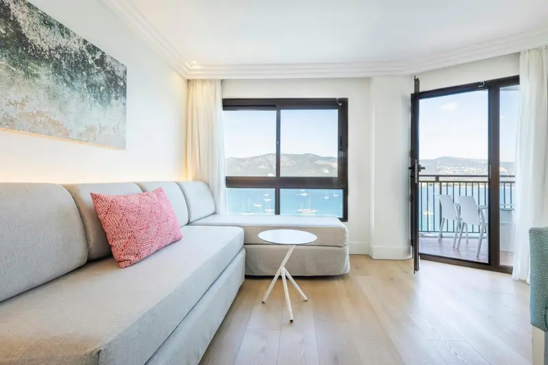 Espace de détente lumineux avec canapé d'angle et vue sur la mer.