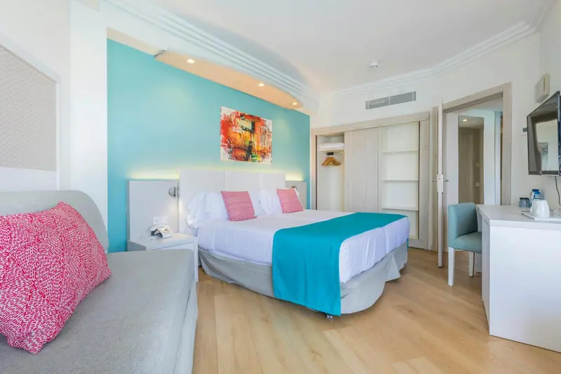 Une chambre lumineuse avec un lit double et un coin salon.