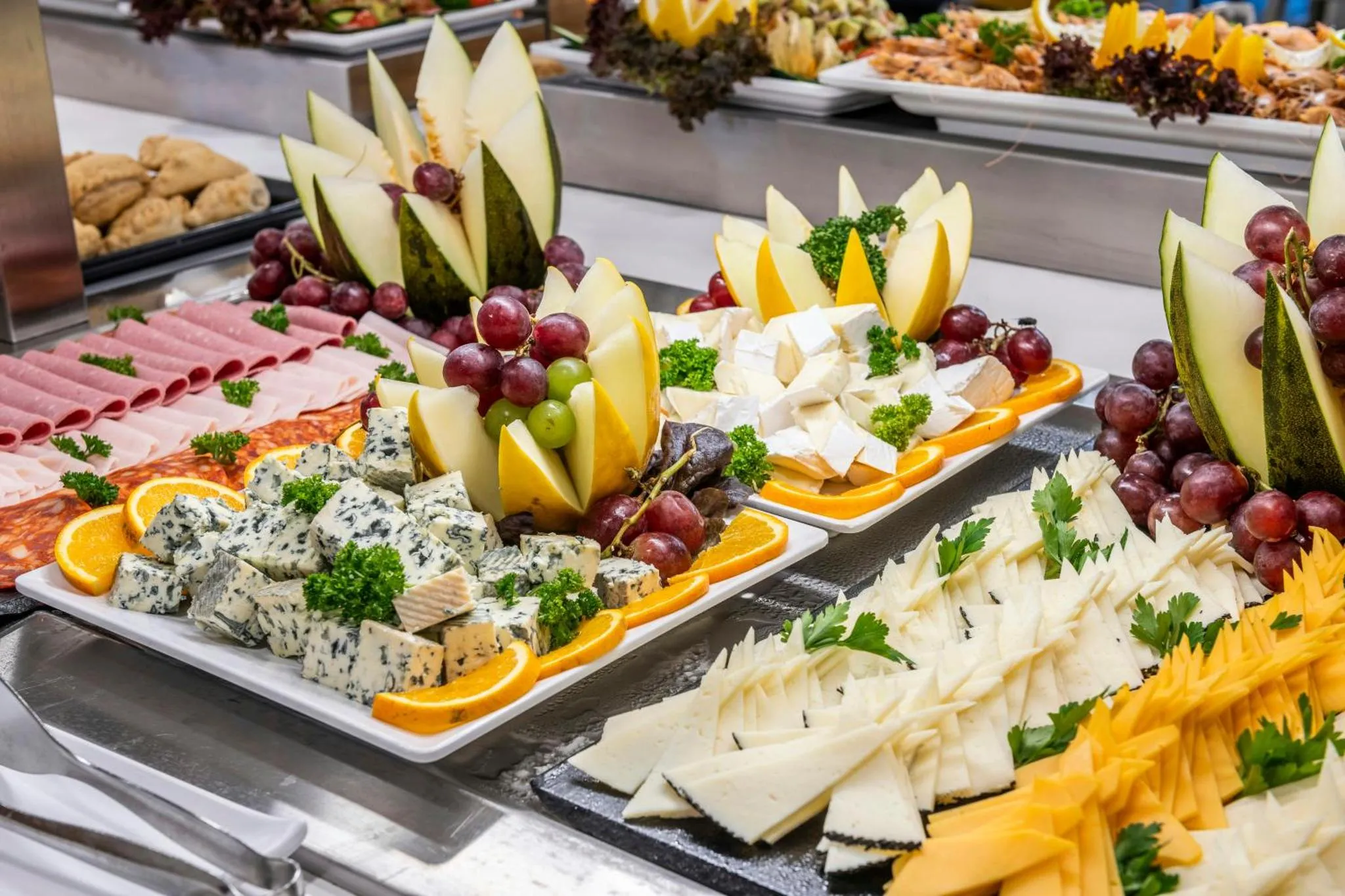 Présentation colorée de charcuterie, fromages et fruits frais sur un buffet.