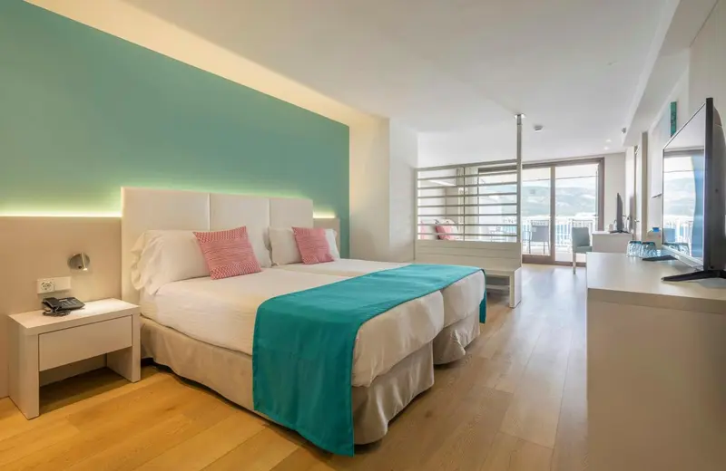 Une chambre lumineuse avec un grand lit et un balcon.