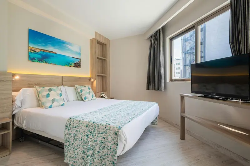 Une chambre lumineuse avec un grand lit et une décoration sobre.