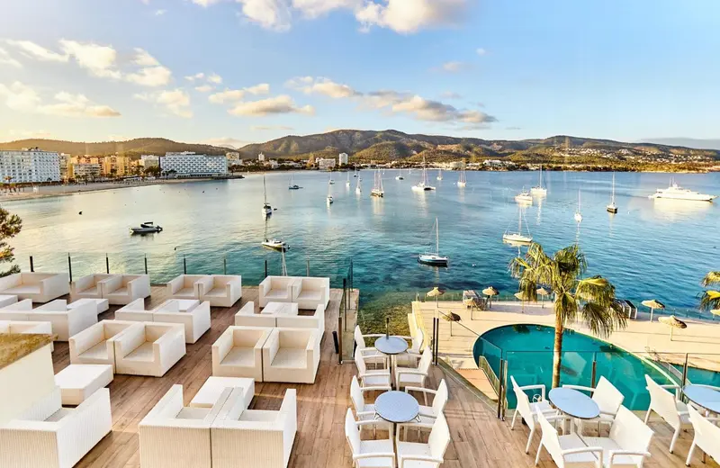 Terrasse aménagée avec des fauteuils blancs et une piscine face à la mer.
