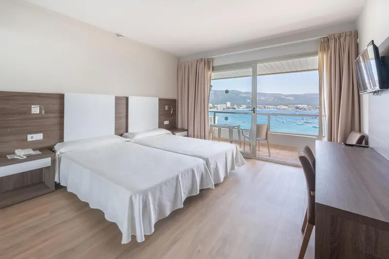 Chambre lumineuse avec lits jumeaux et vue sur la mer.