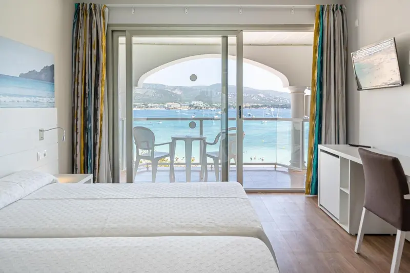 Une chambre lumineuse s'ouvre sur une terrasse avec vue sur la mer.