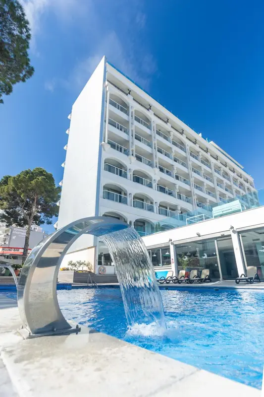 Façade d'un bâtiment blanc avec une cascade dans une piscine.